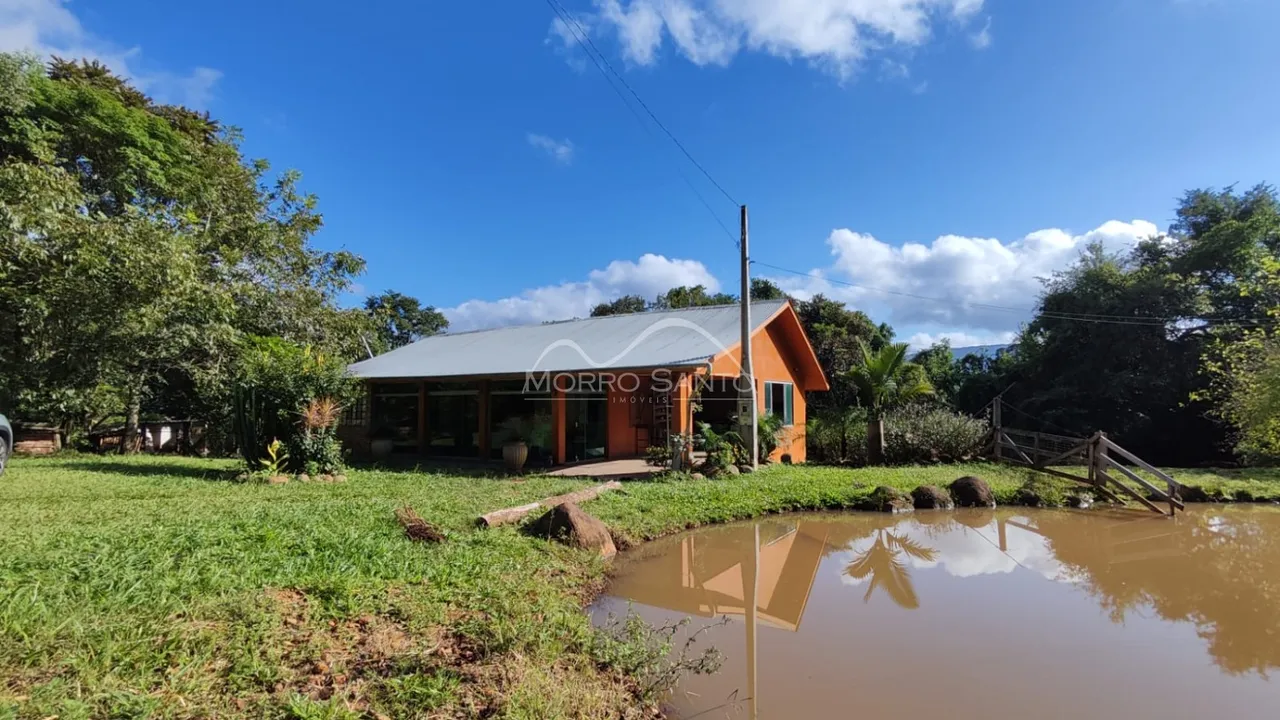 Fachada de uma casa com telhado metálico em Lajeado, Brasil, cercada por vegetação.