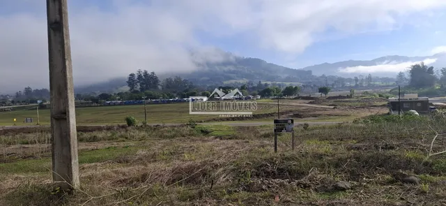 Paisagem rural com colinas cobertas de neblina no fundo.
