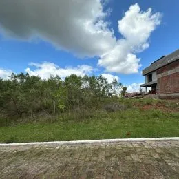 Vista externa de um terreno com vegetação e céu azul.