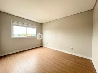 Foto de uma sala de estar com piso de madeira clara e parede neutra.