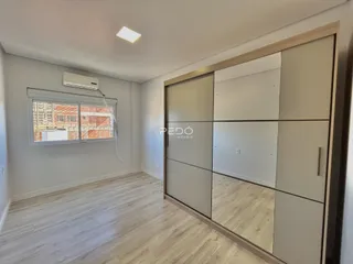 Ambiente interno de um cômodo com piso de madeira clara e armário embutido.