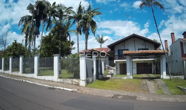 Fachada de uma residência em Lajeado, Brasil, com cerca e vegetação ao fundo.