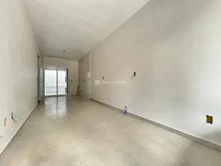 Vista interna de um corredor amplo com paredes brancas e piso claro.