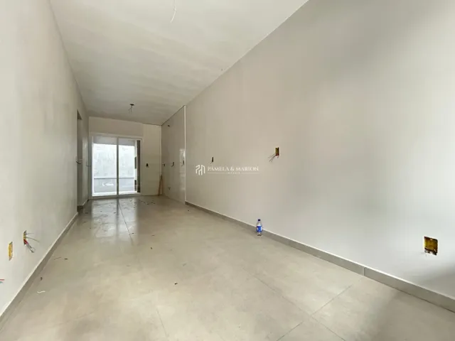 Vista interna de um corredor amplo com paredes brancas e piso claro.