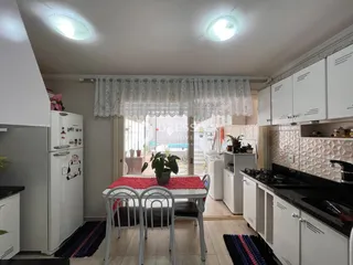 Interior de uma sala de jantar com móveis brancos e bancada escura.