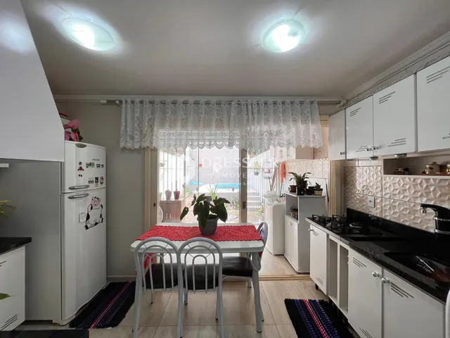 Interior de uma sala de jantar com móveis brancos e bancada escura.