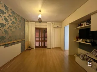 Sala de estar com piso de madeira e parede decorada.