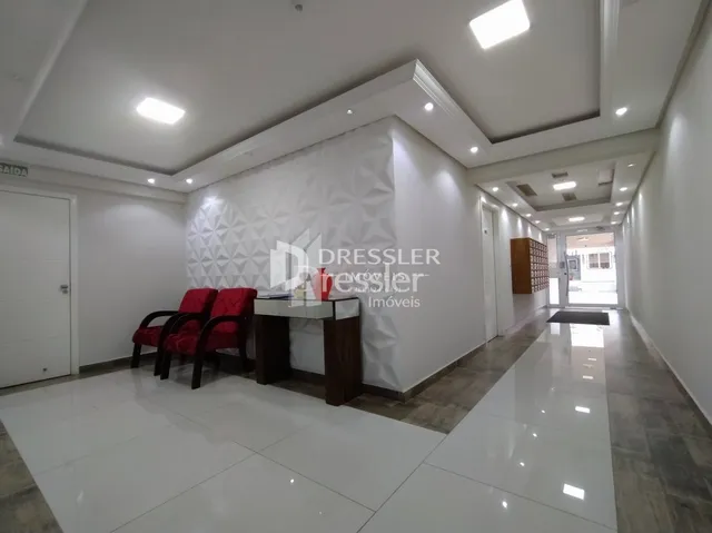Hall de entrada com piso branco e paredes claras.