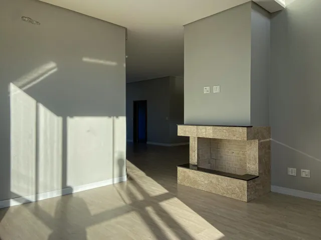 Esta é uma sala de estar com piso de madeira clara e uma lareira em destaque.