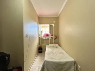 Hall de um quarto com cama e porta de entrada em uma residência.