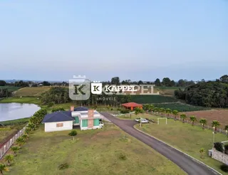 Vista aérea da propriedade mostrando a área externa com campo e corpo d'água.