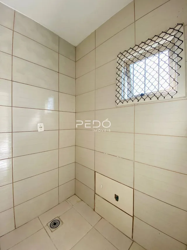 Parede interna com revestimento cerâmico e janela com grade em um imóvel.
