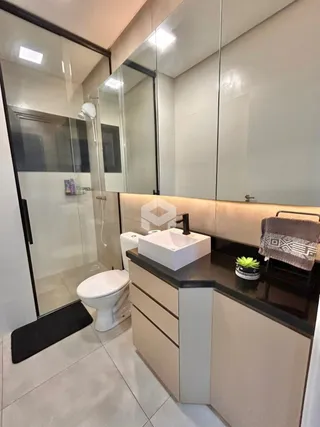 Interior de um banheiro moderno com box de vidro e louças brancas.