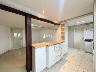 Vista interna de uma cozinha com armários brancos e piso claro.