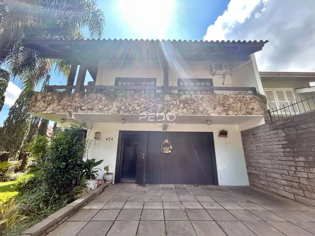 Fachada de uma casa em Lajeado, Brasil com muro de pedra e portão de madeira.