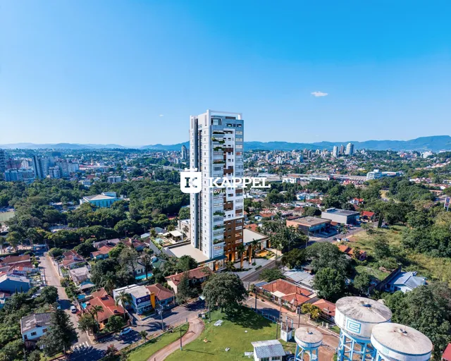 Vista aérea de um edifício residencial alto em Lajeado, Brasil, cercado por vegetação e paisagem urbana.