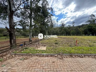 Uma foto externa mostra um campo gramado com árvores e uma cerca de madeira.