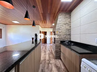 Uma cozinha moderna com bancada escura e piso de madeira clara.