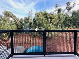 Vista da propriedade com cerca de metal e vegetação densa ao fundo.