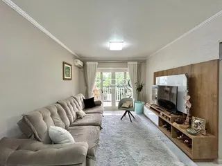 Sala de estar com sofá e porta de vidro de acesso ao exterior.
