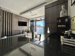 Sala de estar moderna com cozinha integrada e vista para a área externa.