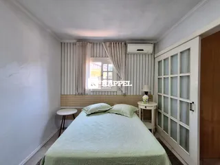 Quarto com cama e cortinas claras em um imóvel.