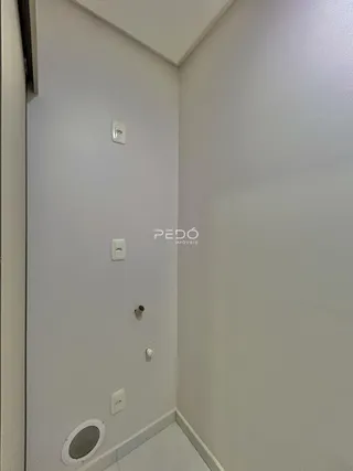 Vista de um corredor interno com paredes brancas e instalações elétricas.