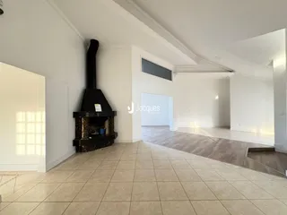 Ambiente interno de uma sala ampla com piso de cerâmica e lareira preta.