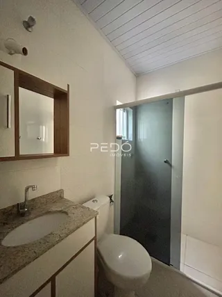 A foto mostra uma área de banheiro com pia e vaso sanitário.