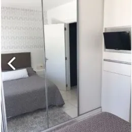 Quarto com cama e espelho refletindo o ambiente.