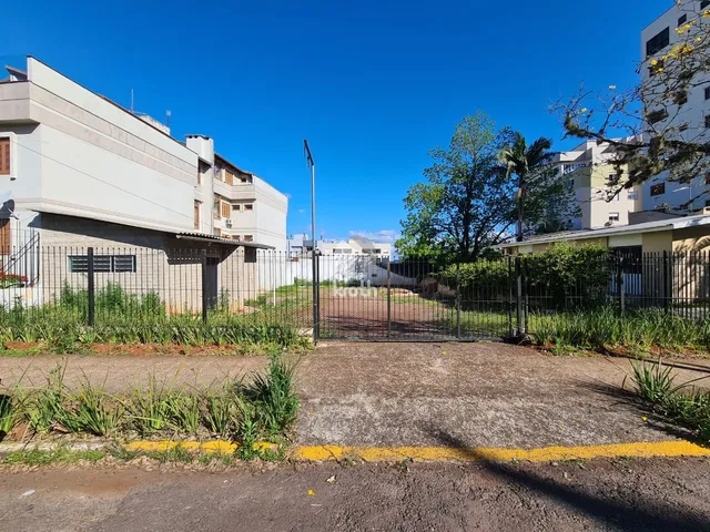 Vista externa da propriedade com cerca de metal e vegetação no jardim.