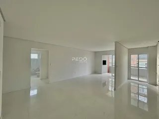 Ambiente interno de uma sala ampla com piso claro e paredes brancas.