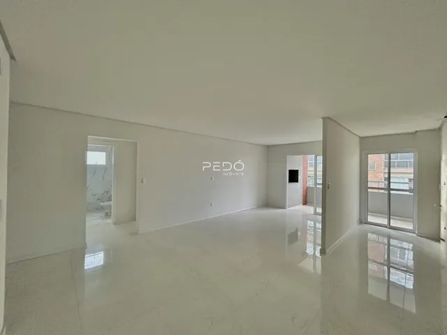 Ambiente interno de uma sala ampla com piso claro e paredes brancas.