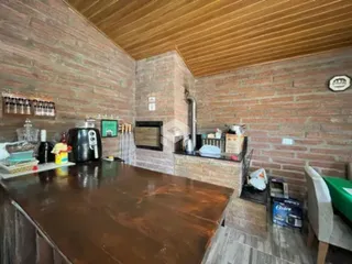 Vista interna de uma cozinha com paredes de tijolo aparente e teto de madeira.