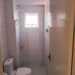 Interior de um banheiro com paredes brancas e uma janela.