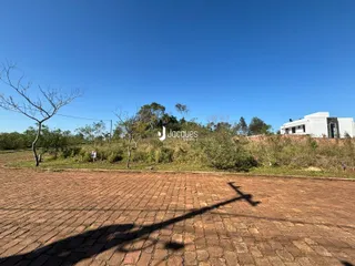 Vista externa de uma propriedade com paisagem de vegetação e um edifício ao fundo.