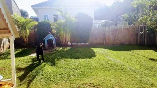 Vista externa de um jardim gramado com cerca de madeira ao fundo.