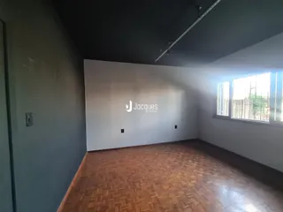 Foto de um ambiente interno com piso de madeira e parede branca.