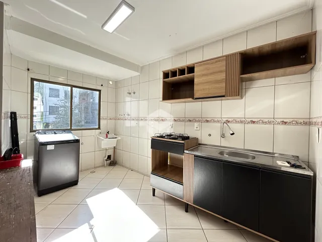 Foto de uma cozinha com revestimento cerâmico e armários de madeira.