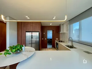 Vista da cozinha moderna com armários de madeira e bancadas brancas.