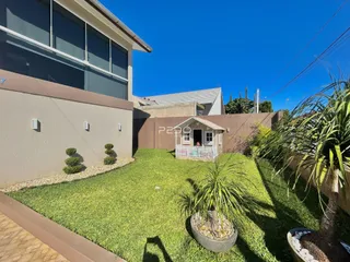 Vista externa de uma residência com jardim gramado.
