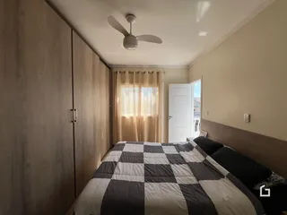 Quarto com armários em madeira e cama no interior de uma residência.