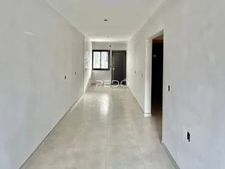Corredor interno de uma residência com paredes brancas e piso de cerâmica.