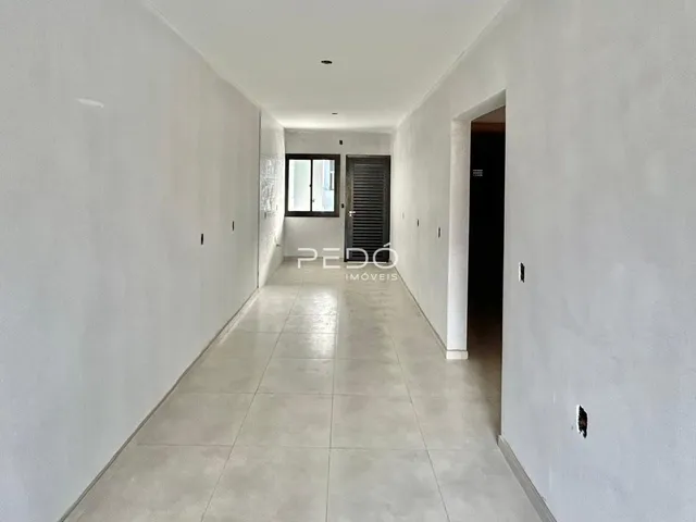 Corredor interno de uma residência com paredes brancas e piso de cerâmica.