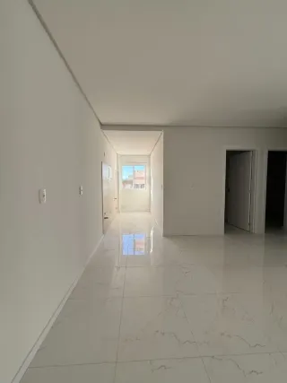 Corredor interno com piso de mármore claro e paredes brancas.