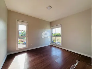 Foto de uma sala com piso de madeira e janelas.