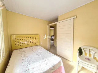 Quarto com cama de madeira e parede amarelada.