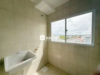 Banheiro com pia branca e janela com vista da cidade.