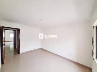 Hall de entrada com paredes brancas e piso claro.