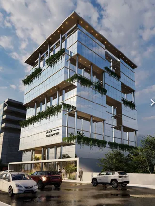 Fachada de um edifício moderno com revestimento de vidro e vegetação.